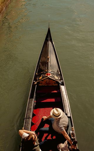 The people are enjoying a leisurely ride on a gondola in Venice.