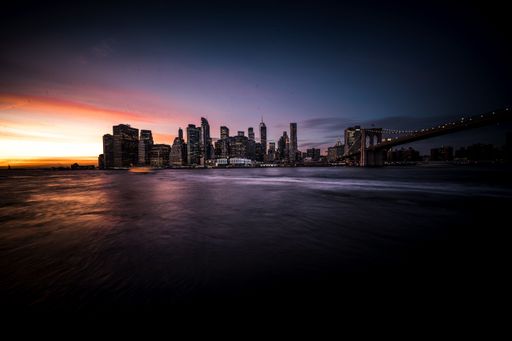 A beautiful view of the city of Manhattan during sunset, with the sun casting an orange hue over the iconic skyline of New York City
