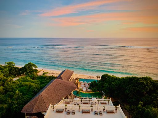 A beautiful outdoor scene featuring a swimming pool and a balcony overlooking a picturesque coastline, illuminated by the setting sun