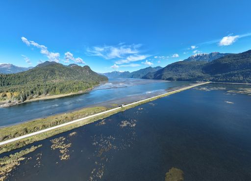 An aerial view of a a road over a lake against a tranquil landscape with rolling hills