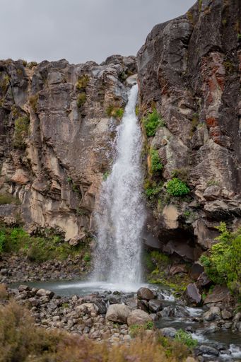 A scenic view of a rocky hillside featuring majestic Taranaki Falls in New Zealand