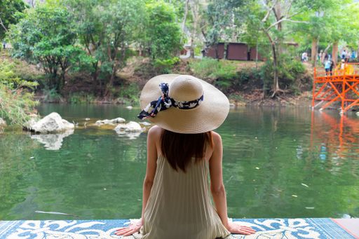 A young female in a white dress sitting on a wooden dock in Tha Farang, Khammouane Province, Laos
