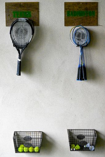 A wall with tennis rackets and a box with tennis balls