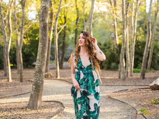 A young European female in a summer dress with leaves print walking in a park