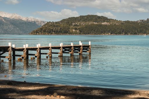 A wooden pier that reaches into tranquil lake surrounded by mountains - perfect for background or wallpaper