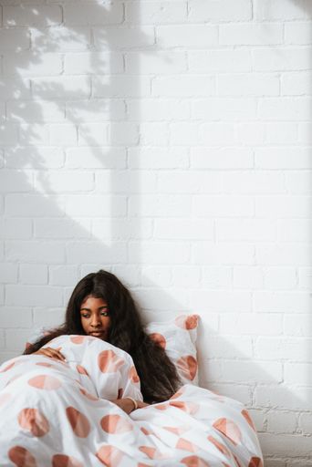 A sad young African female with beautiful long hair lying in the bedafter waking up in the morning