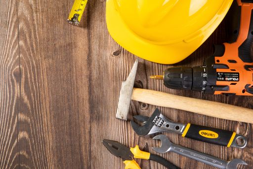 An overhead shot of construction tools on a wooden surface with space for your text