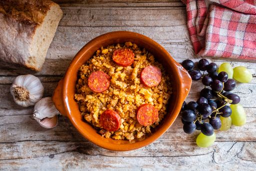 Migas Manchegas with chorizo in a clay pot, served with grapes, garlic and bread. It is a Spanish dish, traditional from Castilla la Mancha.