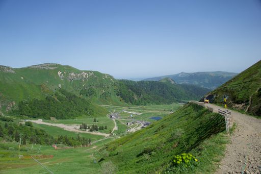 A scenic landscape of a winding green valley surrounded by majestic mountains