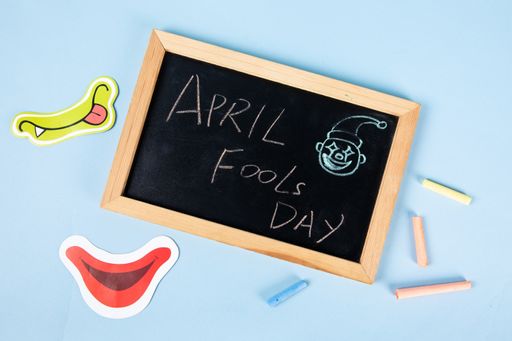 A top view of "April Fools Day" text written on a blackboard with funny faces
