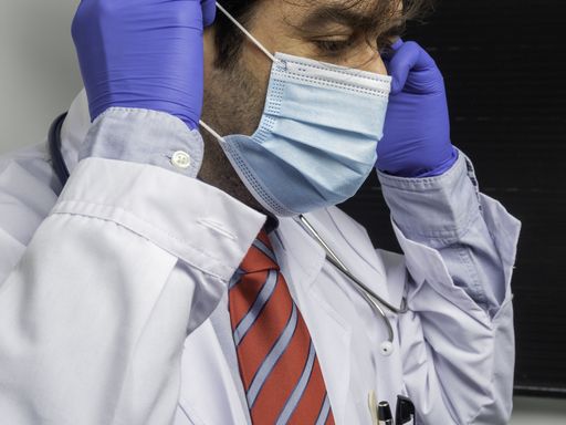 A Hispanic male doctor putting on a protective mask- healthcare concept