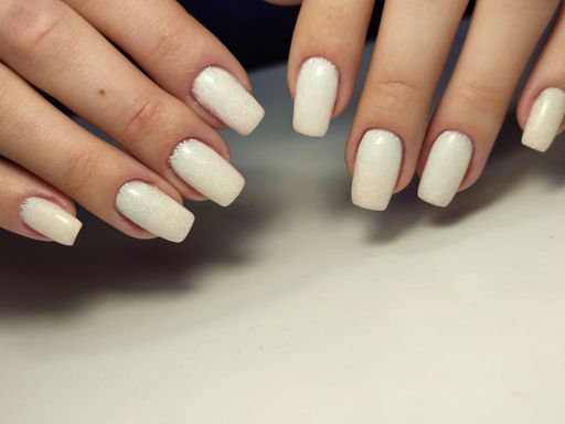 A closeup of woman's hands displaying a trendy gel manicure design in a salon