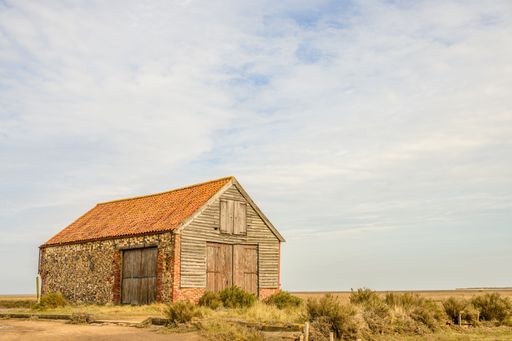 An old coal barn in a grassy meadow. Thornham Old Harbour, England, UK.
