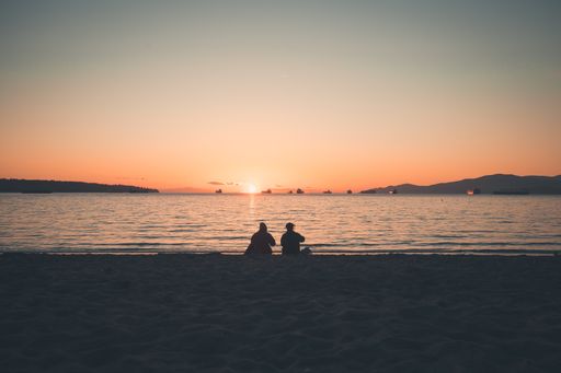 A silhouette shot of women sitting while enjoying the beautiful sunset on the sea
