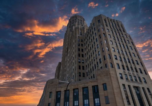 A low-angle shot of Buffalo City Hall against the background of the colorful sky at sunset. New York.