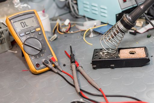 A closeup of a soldering iron and electrical measuring instrument