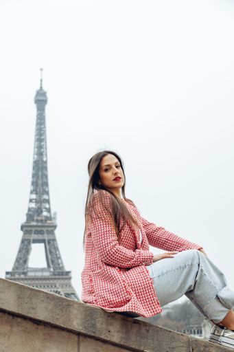A beautiful young Caucasian female posing in front of the iconic Eiffel Tower in Paris, France