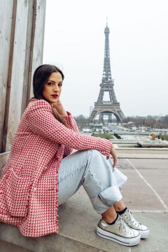 A beautiful young Caucasian female posing in front of the iconic Eiffel Tower in Paris, France