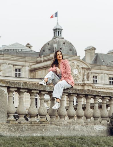 A beautiful young Caucasian female posing in front of a Parisian typical building during the daytime