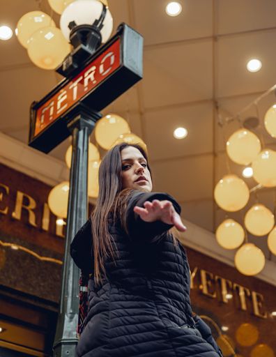A beautiful young Caucasian female posing in front of a metro sign in Paris