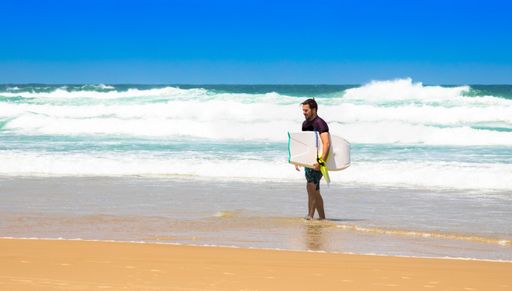 A young caucasian man with a surfboard walking on the coast of Florianopolis, Brazil