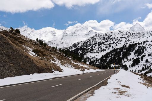 A highway winding through a winter landscape with snow-capped rocks and trees on either side