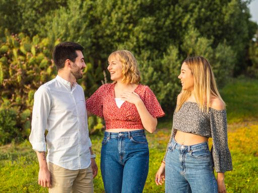 A closeup of friends laughing together while hanging out in the park