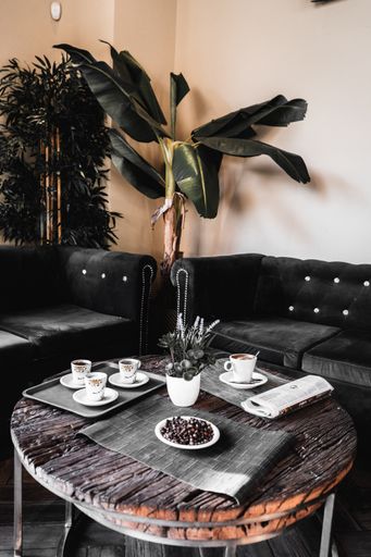 A vertical shot of a round wooden table in a cafe with mugs of coffee and coffee beans