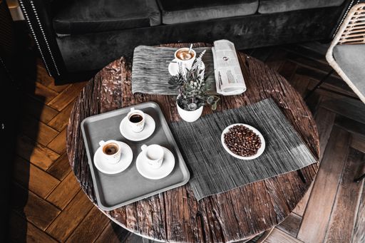A round wooden table in a cafe with mugs of coffee and coffee beans