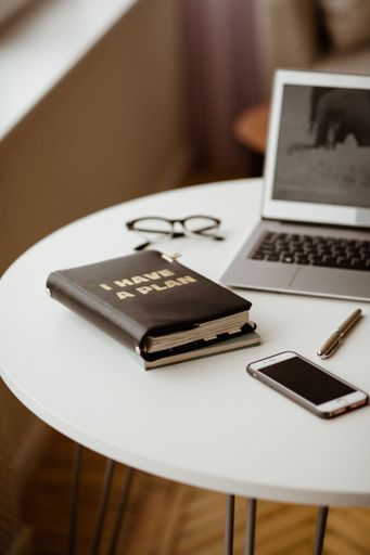 A modern laptop and tablet device resting atop a wooden desk surface, both in a business setting waiting to be used