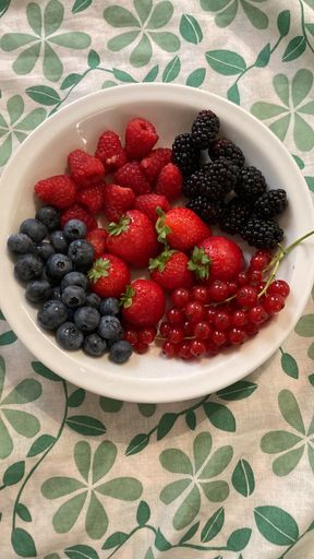 An overhead image of a bowl filled with a selection of ripe berries