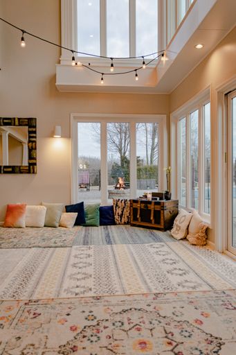 A closeup shot of a white room interior with carpets, pillows, and lamps