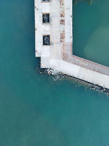 An Aerial view of a concrete pier stretching over the ocean