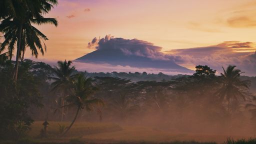 A stunning view of Mount Agung, in Bali, illuminated by a vibrant sunset