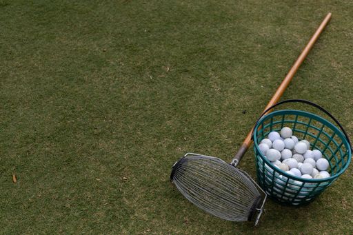 A top view of a bucket of golf balls with a shovel on a  green lawn