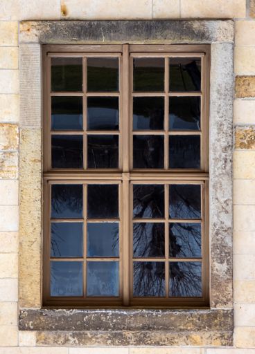 A vertical shot of an old window of a building under the sunlight