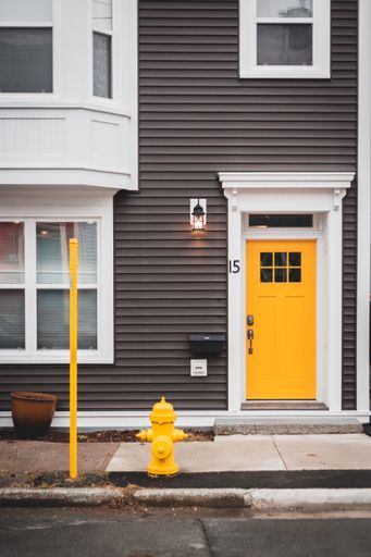 A vibrant yellow fire hydrant near a bright yellow door in a wall