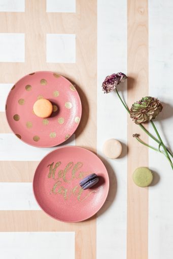 A top view of tasteful French macaroons on pink plates and beautiful flowers on a textured background