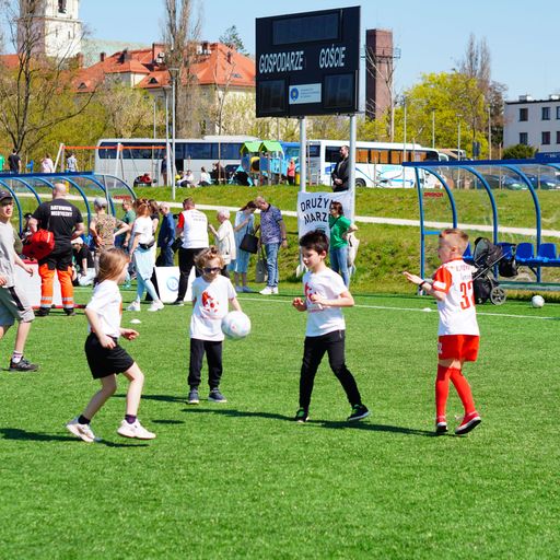 The kids playing soccer outdoors on a lush green grass field in Poland.