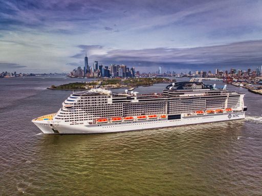 A large luxury MSC cruise ship sailing along the blue ocean waters of a vibrant coastal city