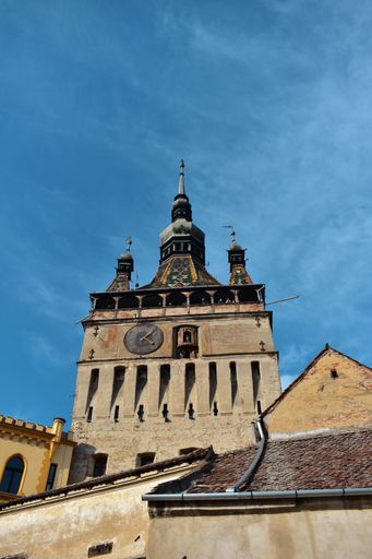 A vertical low angle shot of the Clock Tower Sighisoara in Romania under the pure blue sky