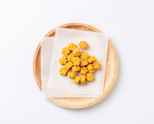 A selection of dog biscuits displayed on a wooden plate on a white background