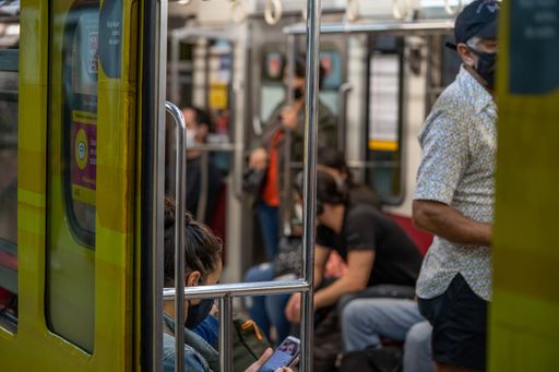 Selected focus of people traveling sitting and standing inside the subway with a face mask without maintaining social distance during the new normal
