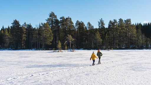 Two people walking across a frozen lake in the middle of winter