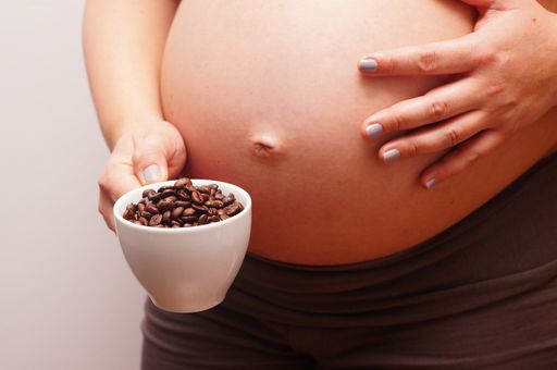 A beautiful shot of a pregnant woman holding cup of coffee beans in front of her stomach