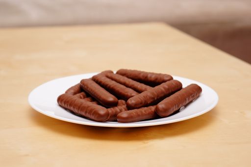 A beautiful shot of chocolate bars on a white plate on a kitchen table