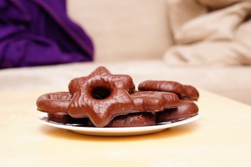 A beautiful shot of star-shaped cookies covered in chocolate on a white plate on the table