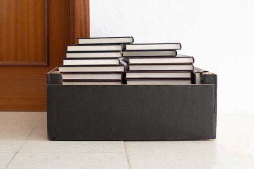 A closeup of a box on the floor full of books, indoors
