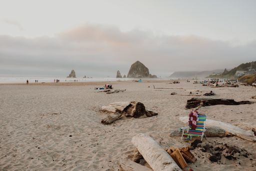 The Cannon Beach surrounded by holidaymakers with the Haystack Rock under a cloudy sky on the background