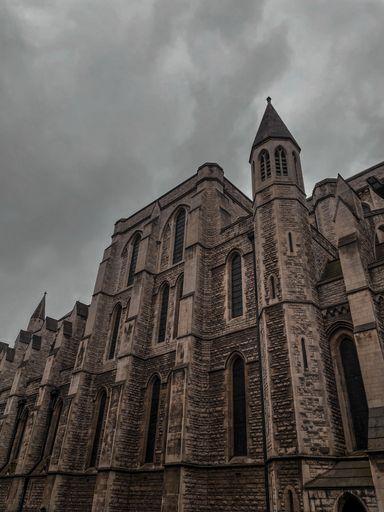 An old castle stands in front of a cloudy sky.